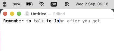 A Mac menu bar with the Wi-Fi icon crossed out, and below it a TextEdit window where the typed words &ldquo;Remember to talk to Jo&rdquo; are continued by the grey suggestion &ldquo;hn after you get&rdquo;.